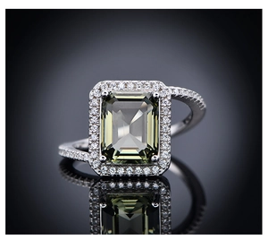 Macro detail of emerald cut light green gemstone ring with twisted diamond-set band
