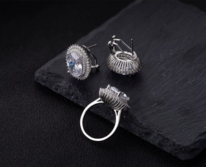 Detailed set of oval cut solitaire ring and matching earrings on black stone plate