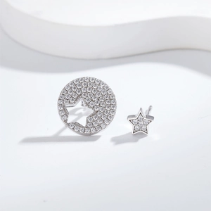 Asymmetric S925 sterling silver star earrings with micro-paved diamonds on white stand