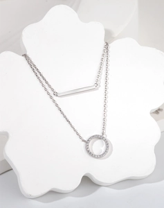 Detail view of silver double-layered necklace with a horizontal bar and pavé circle pendant