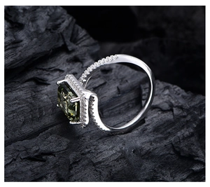 Macro side view of silver emerald cut ring with green stone and halo setting