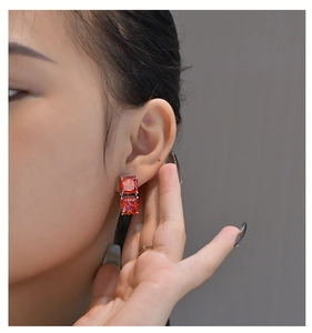 Close-up of model wearing square-cut red zircon drop earrings in silver setting