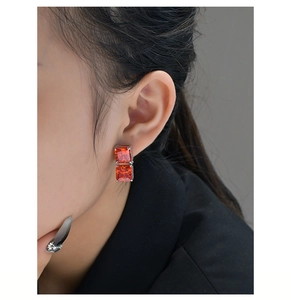 Close-up of dual-stacked orange square cut 8ct ice cut earrings on a female ear