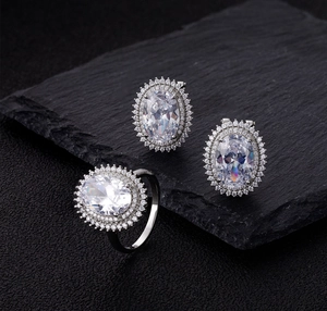 Macro shot of oval-cut diamond jewelry set featuring double halo silver rings and studs