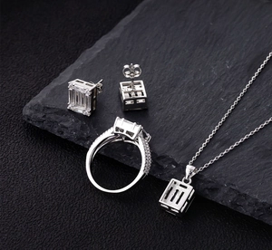 Macro shot of 925 silver jewelry set with emerald-cut zircon on dark stone background