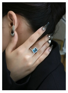 Close-up of emerald cut deep blue gemstone ring with micro-paved diamonds on hand