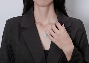 Gros plan d'un collier pendentif halo en diamant de 9,5 mm porté sur un blazer noir chic