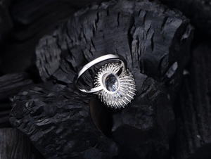 Gros plan de la bague diamant ovale de luxe sur un fond de charbon texturé sombre