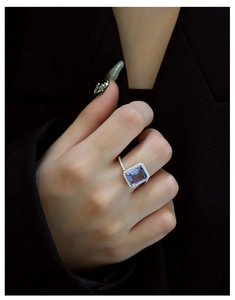 Macro detail of rectangle emerald-cut purple gemstone ring with diamond pavé setting