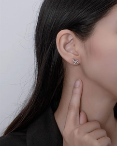 Detailed view of silver butterfly stud earrings with zircon inlay on model's ear
