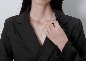 Detailed close-up of double-layer silver necklace with zircon circle and bar pendants