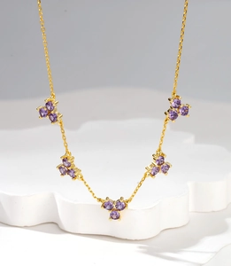 Macro view of five purple gemstone clusters on an 18k gold plated snowflake necklace