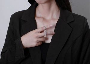 Close-up of a model wearing a micro-pave silver paperclip pendant necklace with sparkling diamonds