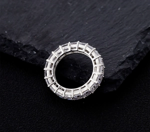Dettaglio macro di anello eternity in argento con pietre taglio smeraldo su roccia