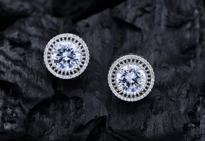 Macro shot of 10mm round cut sparkling ear studs with double halo on dark textured stone