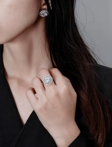 Close-up of elegant 10mm round halo stud earrings and matching ring on a model