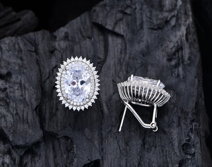 Close-up of 925 sterling silver stud earrings with oval carbon diamond and double halo