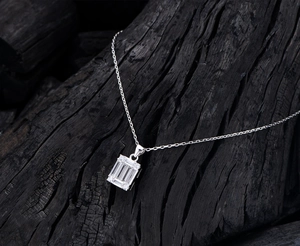 Close-up of S925 sterling silver emerald-cut cubic zirconia pendant on dark wood background