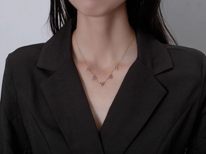 Detail of 18k gold plated necklace with purple crystal snowflake charms on a model