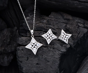 Detail of silver starburst necklace and earrings set on dark textured charcoal base