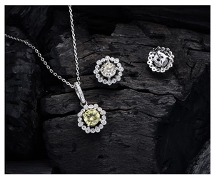 Detailed view of yellow crystal halo necklace and stud earrings set on dark texture