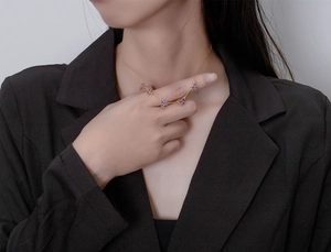 Detail view of 18k gold plated necklace with five purple gemstone flower pendants on model