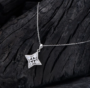 Close-up of S925 silver star necklace with zircons on a dark textured background