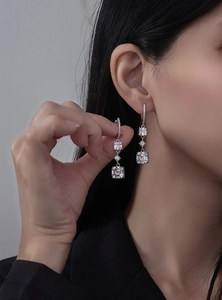 Détail macro de boucles d'oreilles pendantes en argent avec zircons sur un modèle