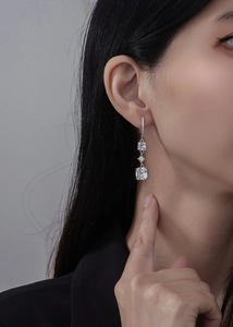 Détail de boucles d'oreilles pendantes en argent 925 avec zircons taille émeraude sur mannequin