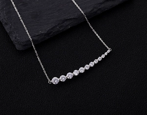 Detail of silver bar necklace with eleven gradient pavé zircons on black stone background