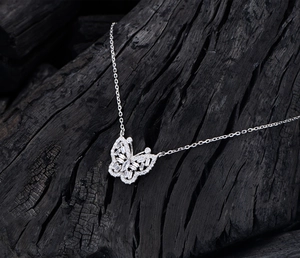 Vue macro du pendentif papillon en argent avec zircons sur bois de charbon noir