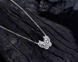 Vue macro du pendentif papillon en argent avec zircons cubiques sur bois noir
