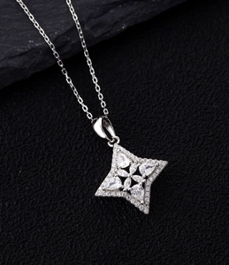 Macro shot of silver four-pointed star necklace with micro-paved diamonds on black stone