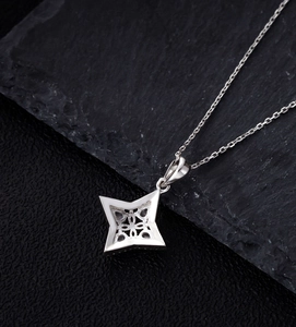 Detail of star pendant back showing hollow cross texture and purple gemstones on stone