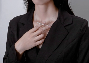 Close-up of sparkling 925 silver curved necklace with white stones on a black blazer