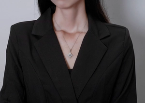 Detail of star pendant necklace with micro-pave diamonds worn on elegant black outfit