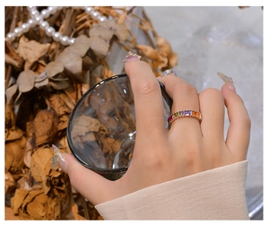 Detailed close-up of rainbow baguette gemstone ring on finger with elegant props