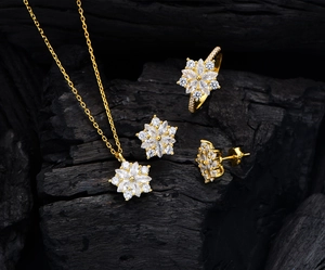 Dettaglio macro di un set di gioielli in argento S925 con collana a stella e anelli floreali