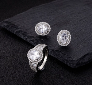 Detailed view of luxury oval diamond rings and earrings on a black stone surface