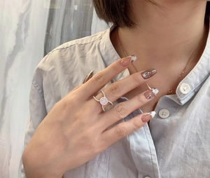 Macro shot of micro-paved zircon round disc silver ring on model's hand wearing blue shirt