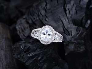 Macro view of oval 7x9mm sparkling gemstone ring with halo diamonds on charcoal background