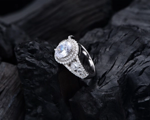 Macro shot of oval-cut diamond ring with sparkling double halo and silver band