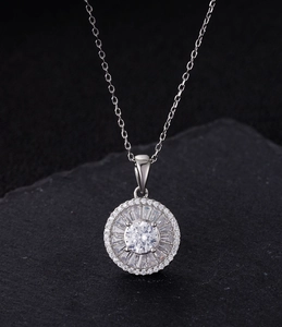 Close-up of S925 silver sunburst pendant with radiant zircons on a textured stone surface