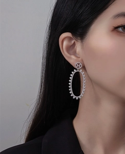 Close-up of elegant silver oval hollow earrings with micro-pave crystals on model