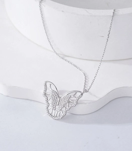 Detailed close-up of a silver butterfly pendant with micro-set zircon on a stone stand