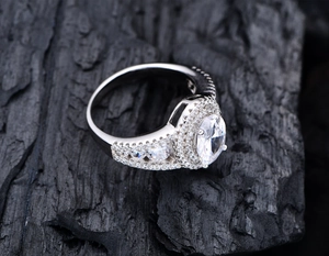 Macro shot of oval-cut diamond ring with pavé setting on charcoal background