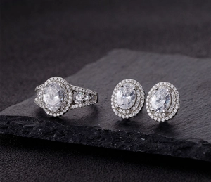 Macro detail of oval halo ring and matching earrings on a dark slate background