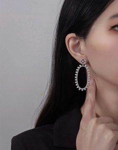 Close-up of model wearing silver oval hollow earrings with micro-pave crystals