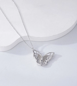 Macro detail of silver butterfly necklace pendant showing intricate stone settings and chain