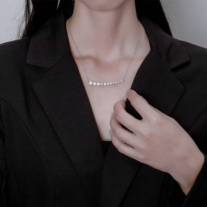 Elegant silver necklace with a curved row of graduated zircon stones on a model